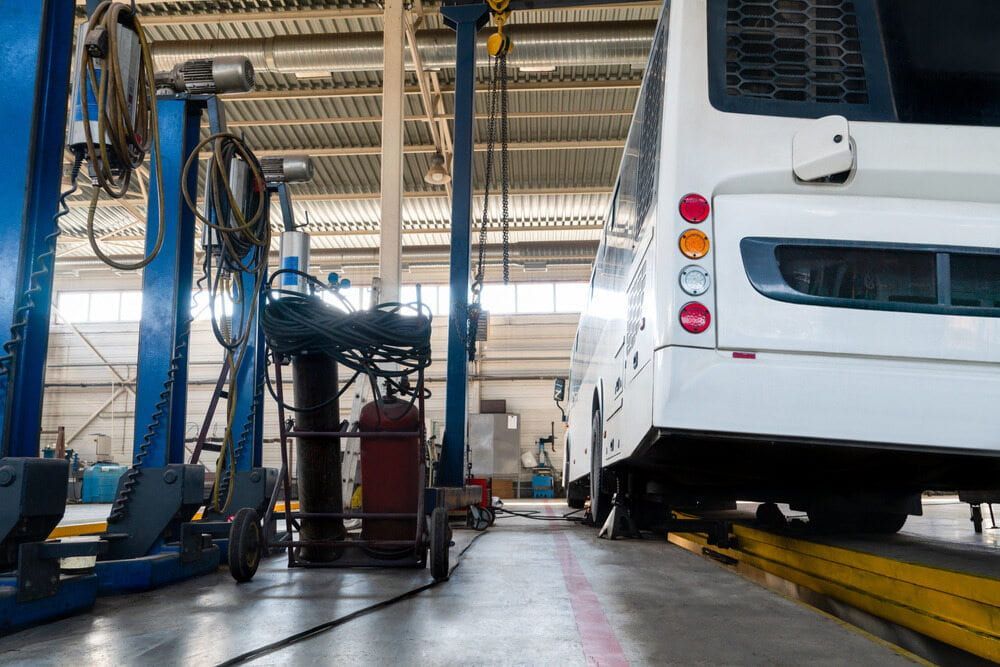 A White Bus Is Sitting On A Lift In A Garage — Cairns Mechanical Workshop In Bungalow, QLD