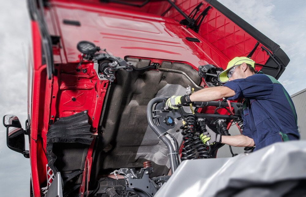 A Man Is Working On The Engine Of A Red Truck — Cairns Mechanical Workshop In Tablelands, QLD