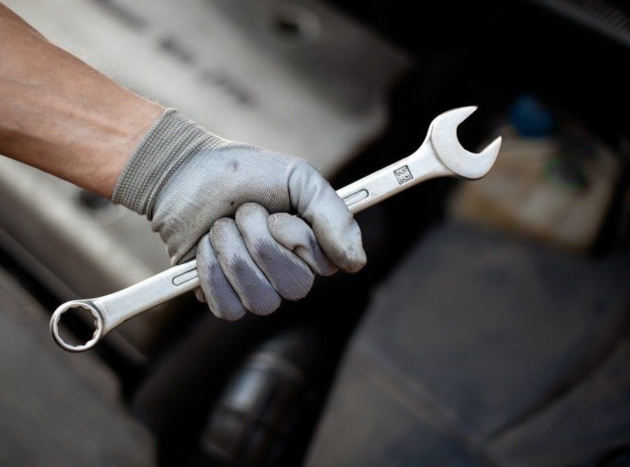 A Person Wearing Gloves Is Holding A Wrench In Their Hand — Cairns Mechanical Workshop In Bungalow, QLD