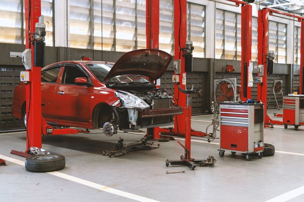 A Red Car Is Sitting On A Lift In A Garage — Cairns Mechanical Workshop In Cairns, QLD