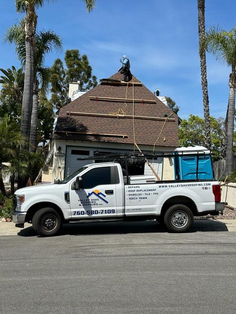 A white truck is parked in front of a house under construction.