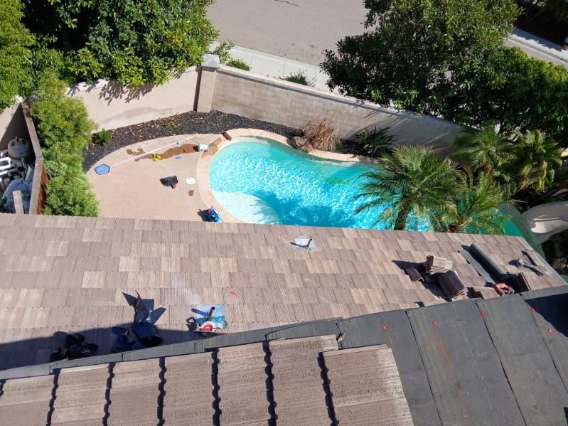 An aerial view of a roof with a pool in the background