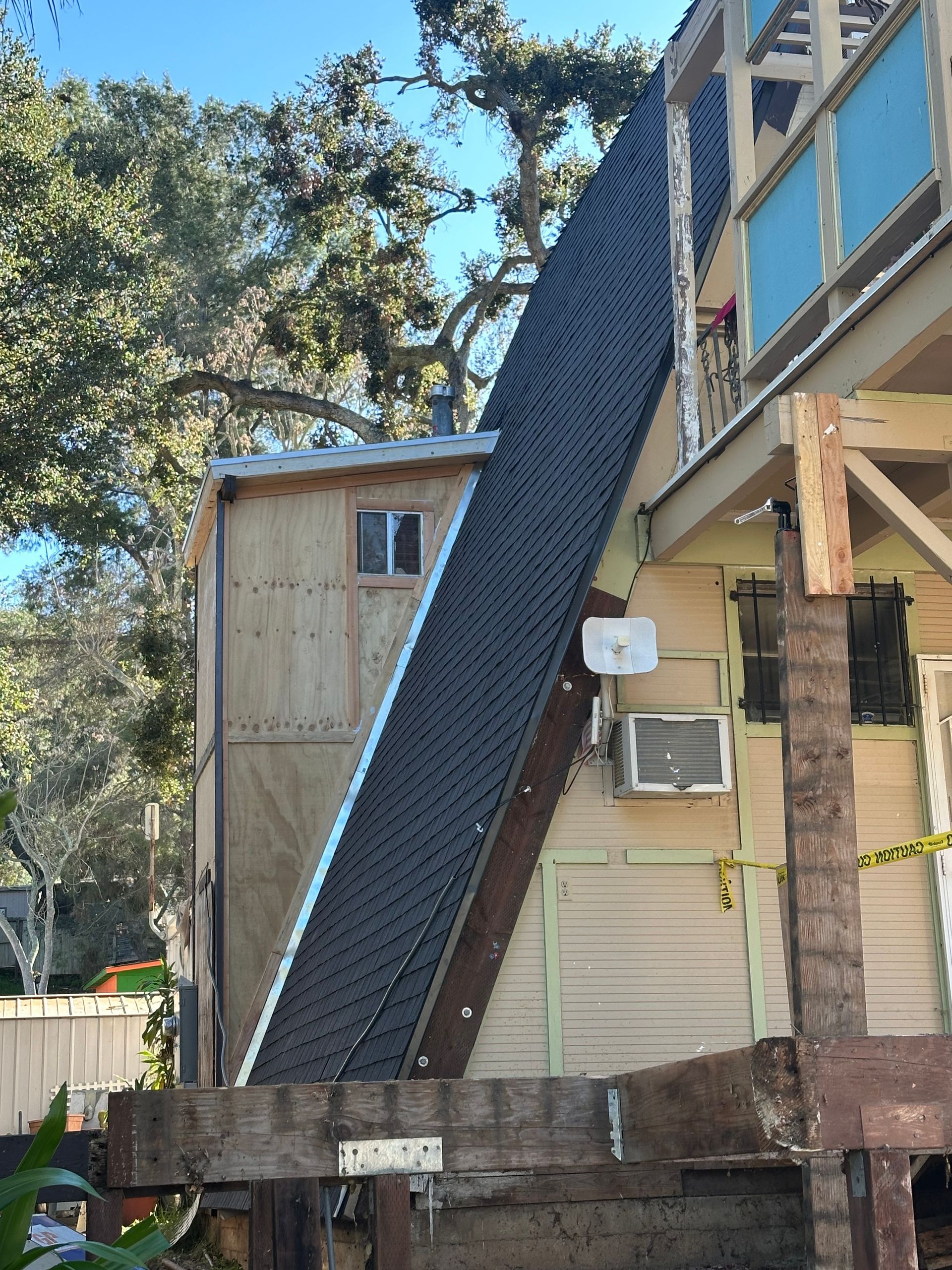 A multi-story building with a steep, angled roof covered in dark shingles.