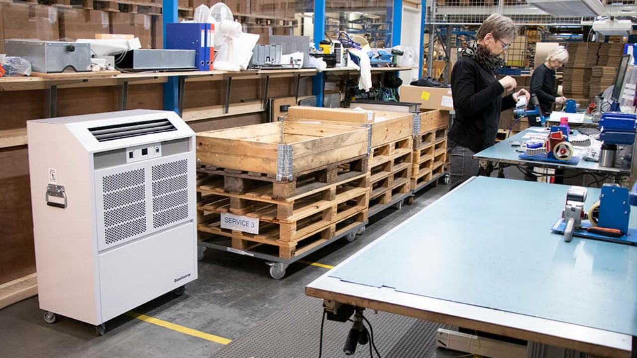En kvinde arbejder på et lager, mens en mand står bag et bord.
