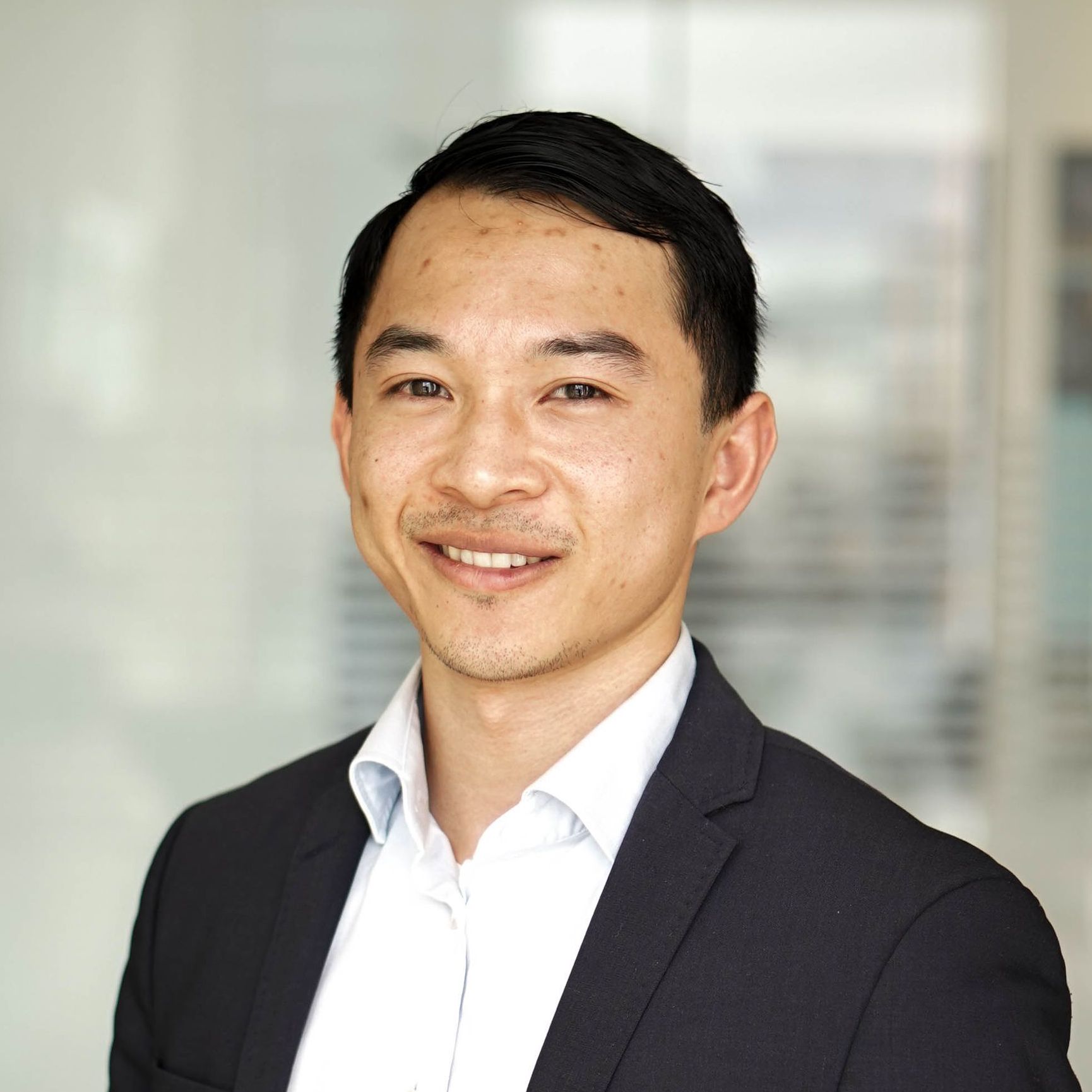 A man in a suit and white shirt is smiling for the camera.