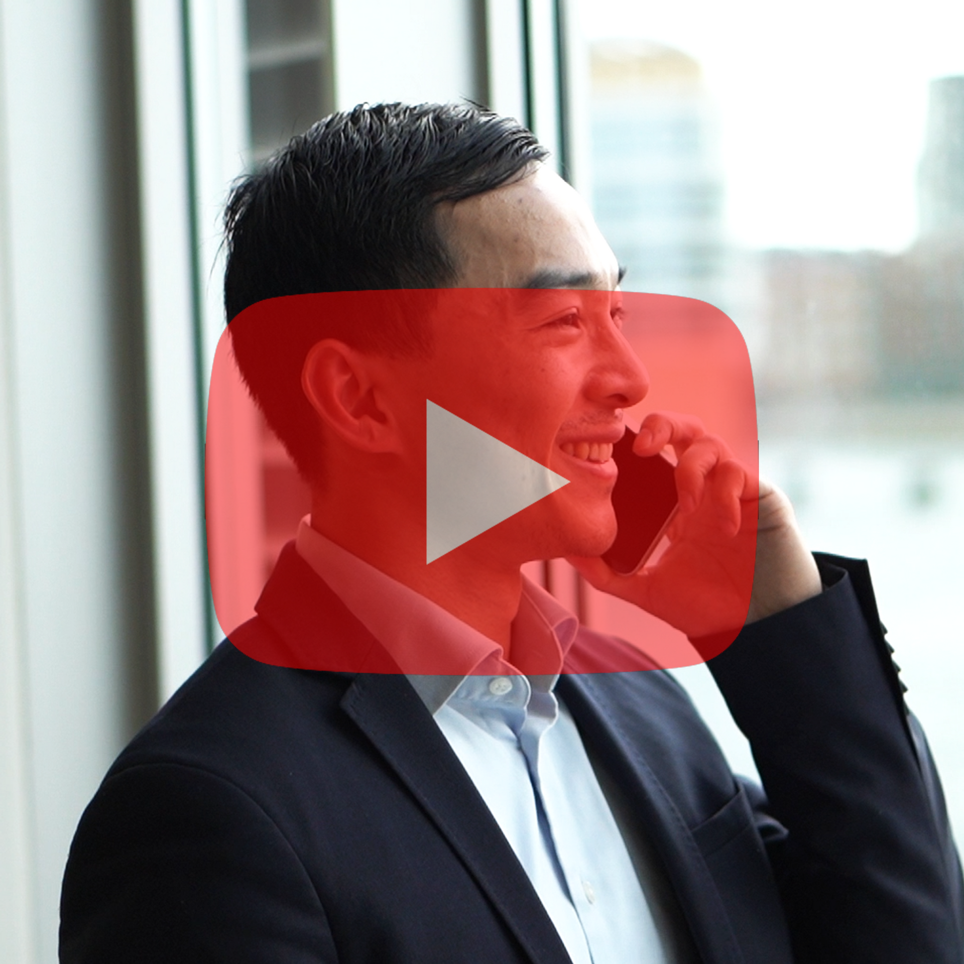 A man in a suit is smiling while talking on a cell phone