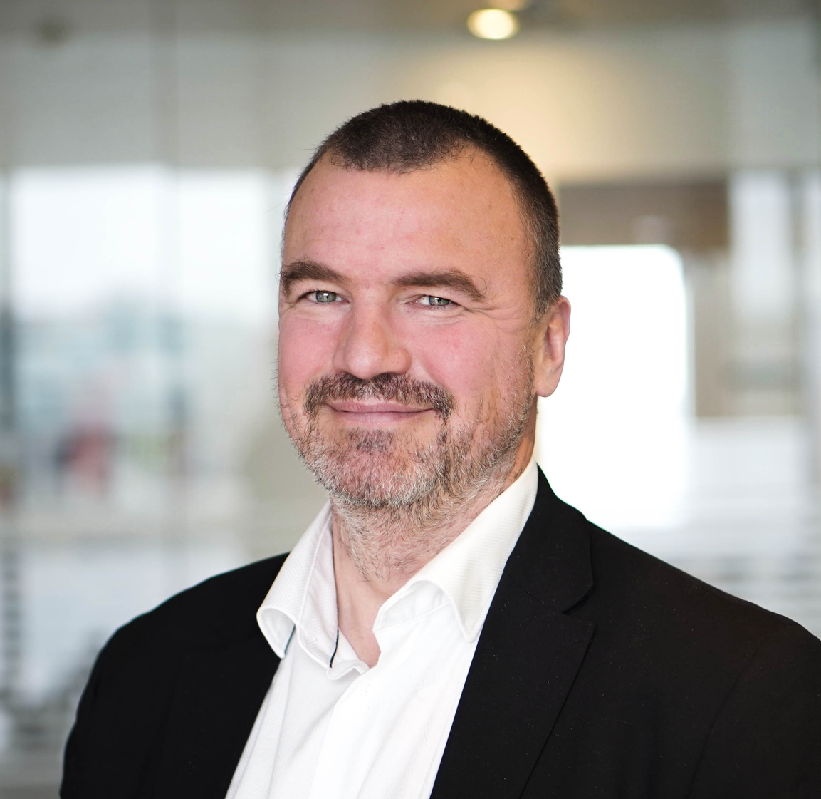 A man in a suit and white shirt is smiling for the camera.