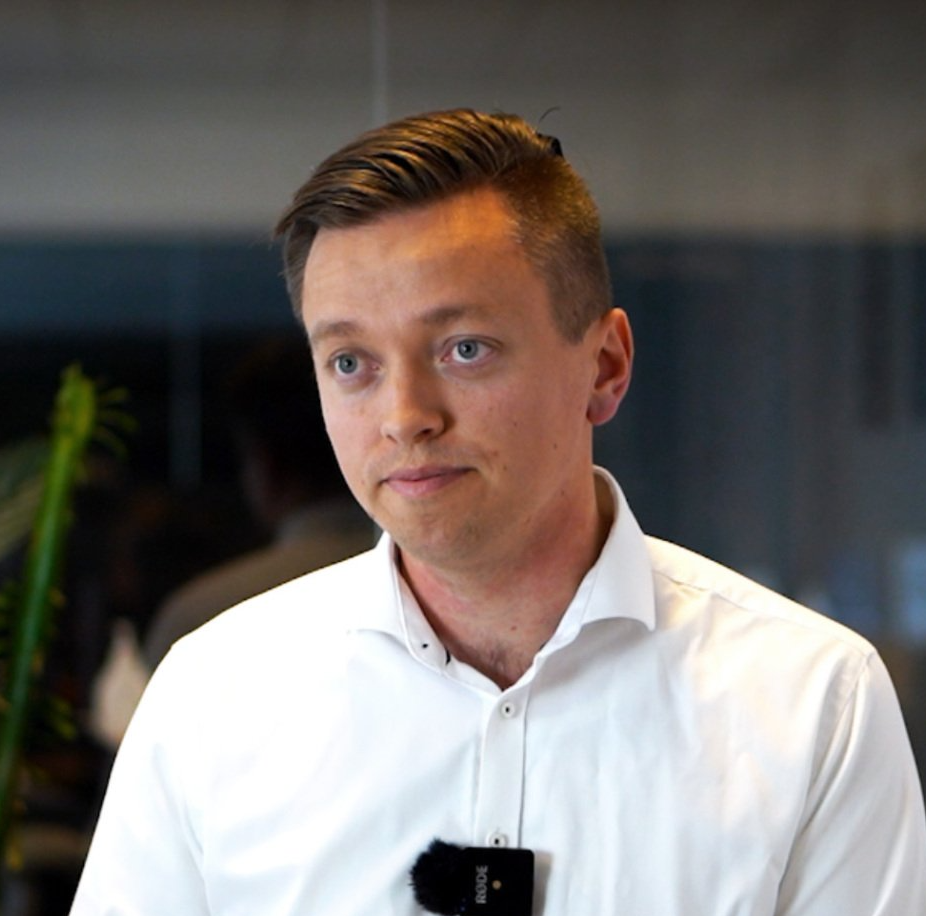 En mand iført en hvid skjorte har en mikrofon fastgjort til halsen