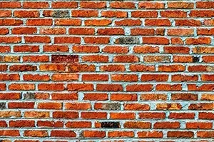 A textured wall made of red and brown rectangular clay bricks arranged in a horizontal running bond pattern.