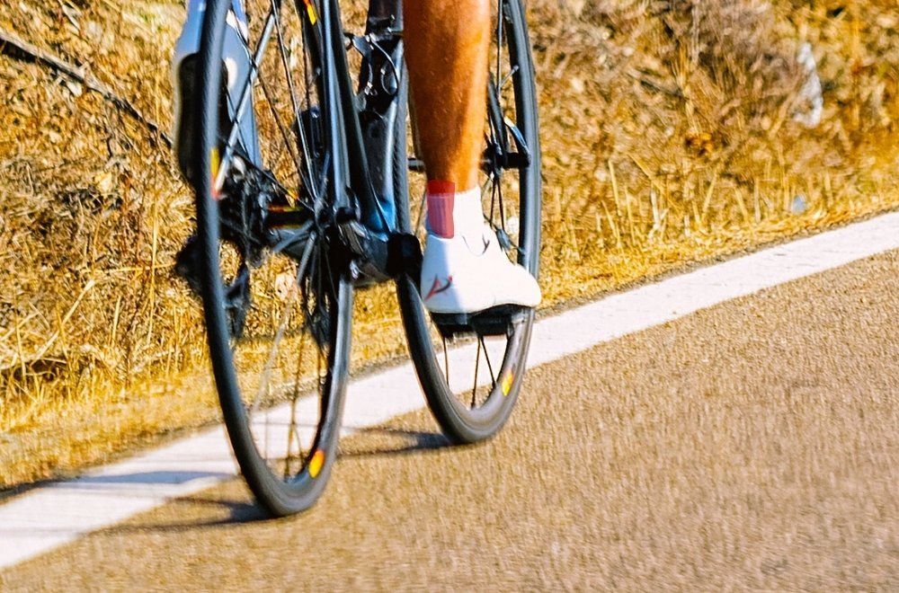 An image is a cyclist riding a bike with the Achilles tendon highlighted