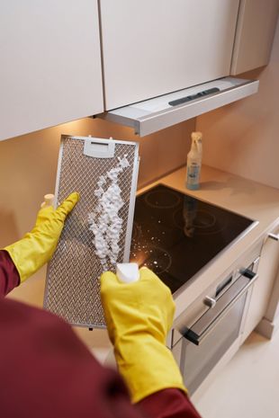 Spraying cleaner on a kitchen appliance