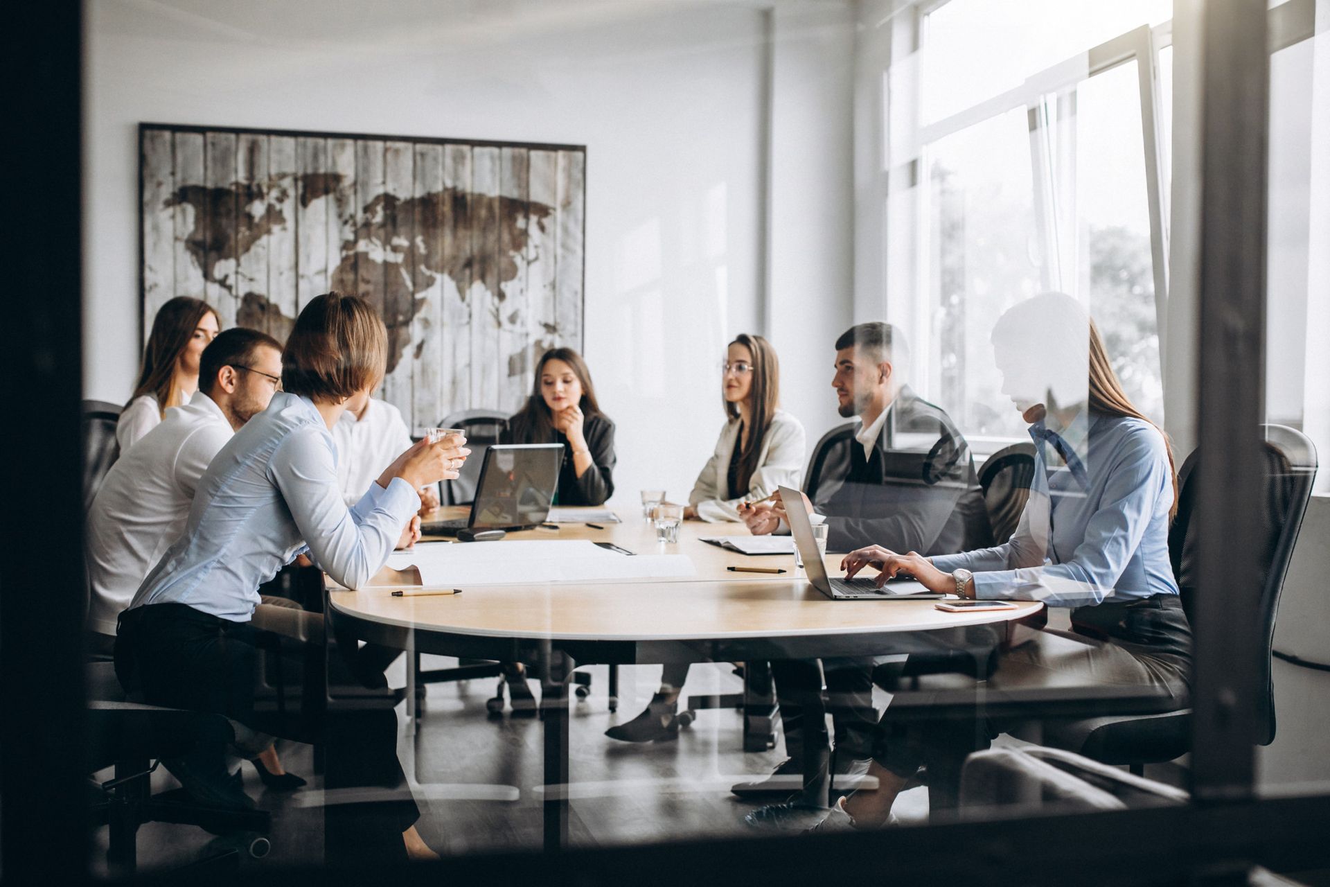 Um grupo diversificado de profissionais sentado em volta de uma mesa de conferência em um escritório, discutindo assuntos.
