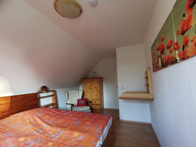 Schlafzimmer 1 mit aufgeklapptem Wickeltisch, Kleiderschrank und Sessel