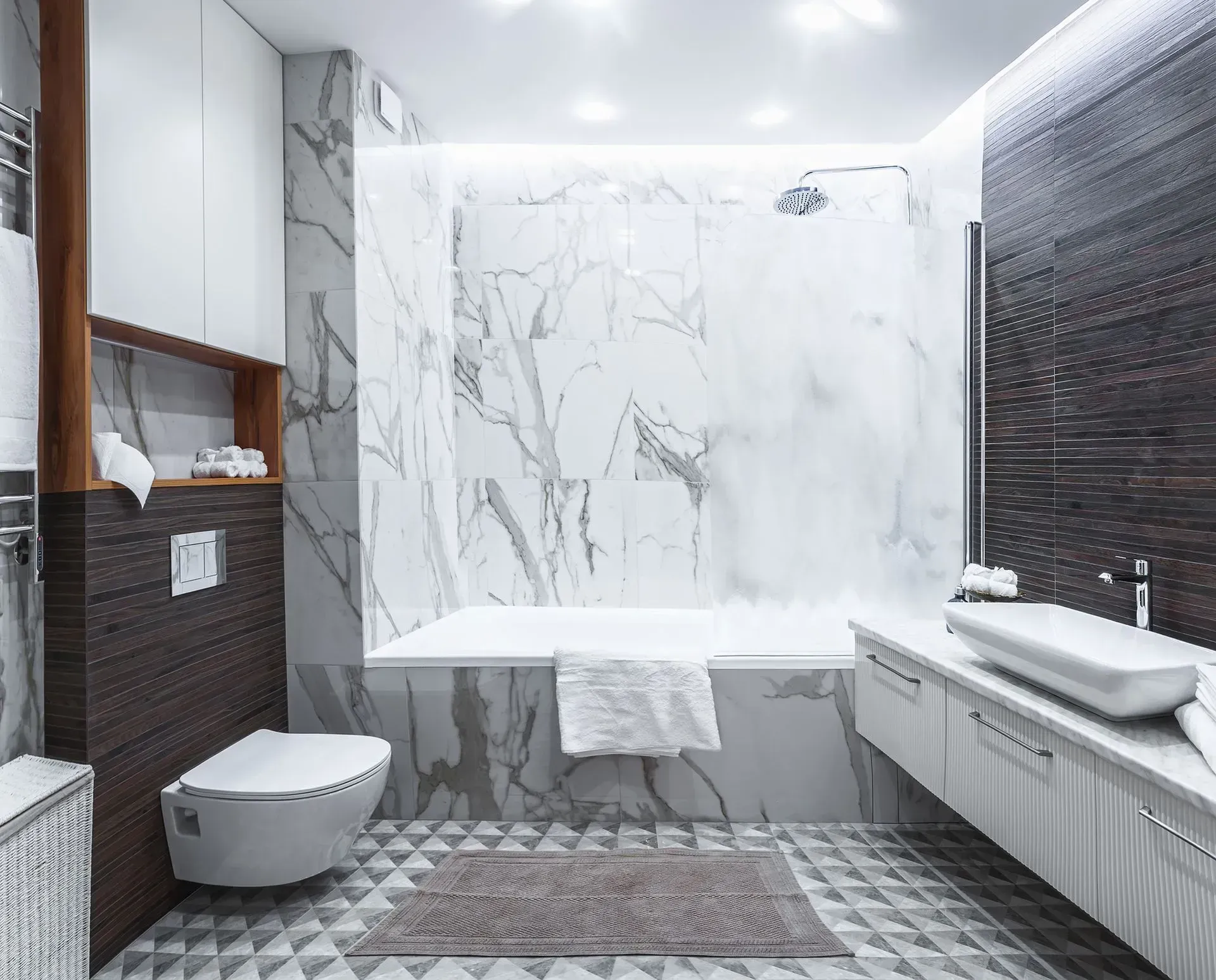 Modern minimalist bathroom with marble walls, floating sink, toilet, walk-in shower, and patterned tile floor