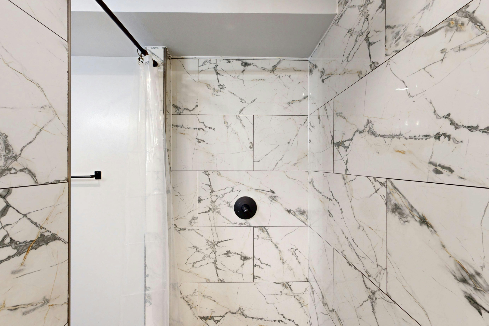 Modern marble-tiled shower with glass door and black fixtures