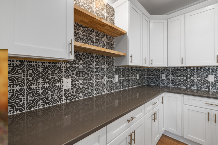 White kitchen with black patterned tile backsplash and dark countertops