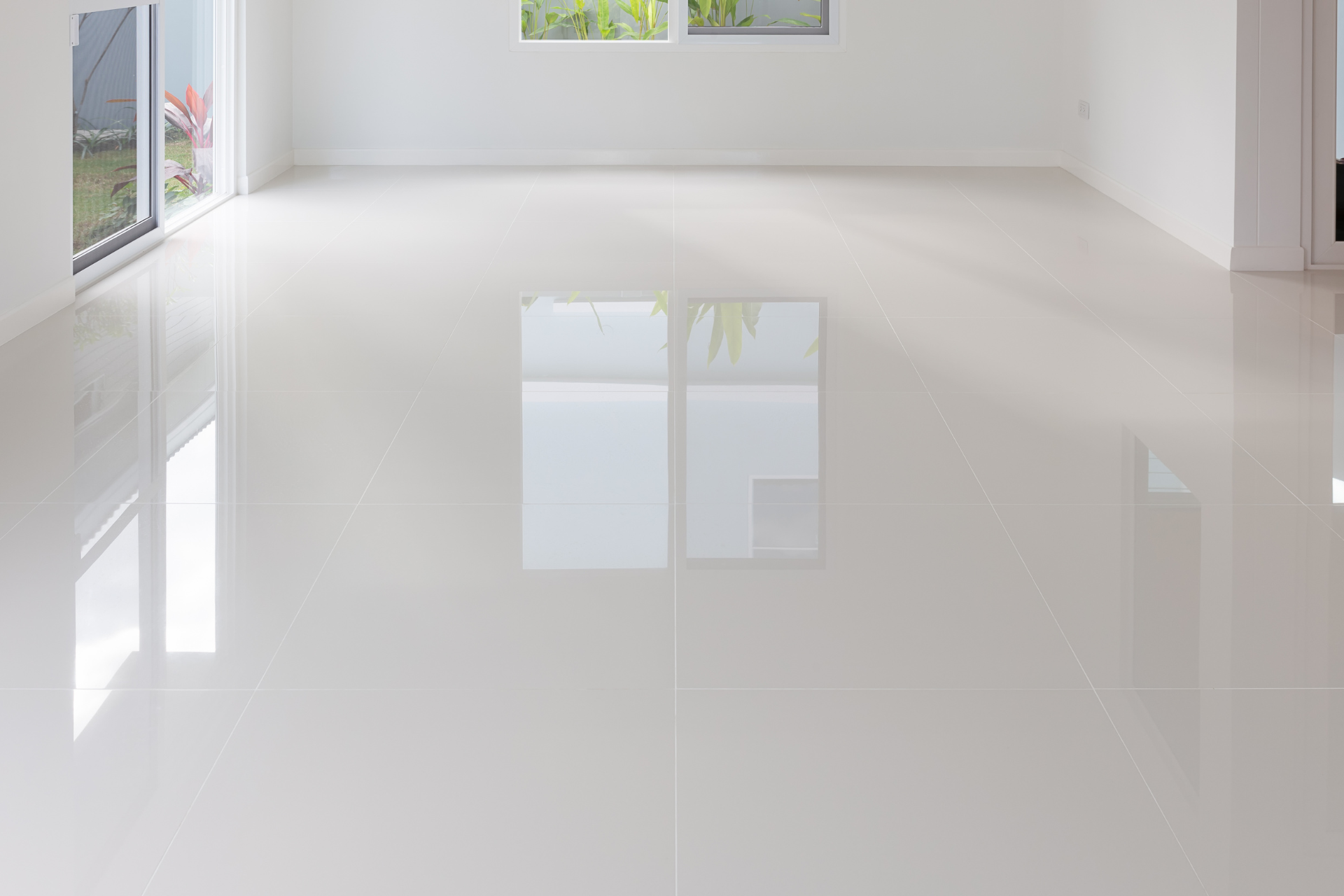 Empty modern room with glossy white floor and large windows reflecting light