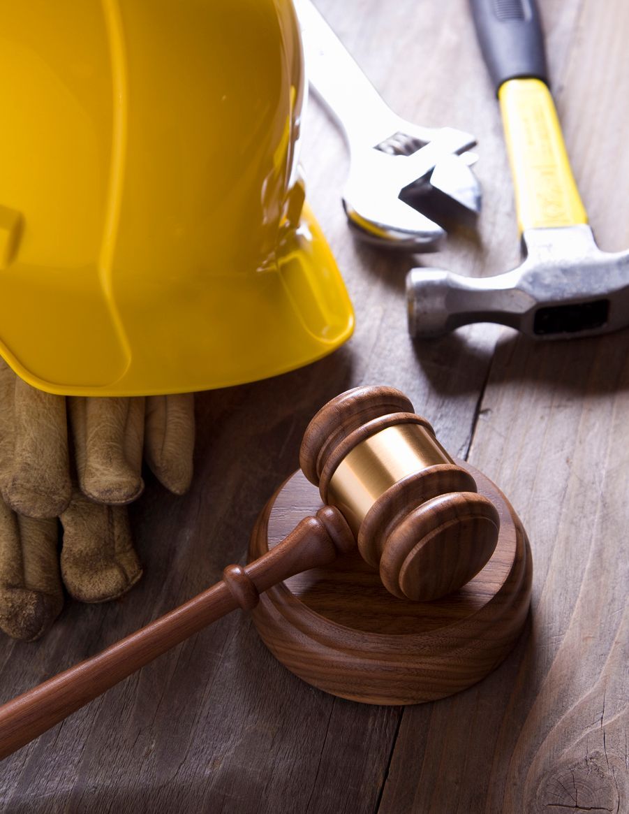 A yellow hardhat and tools next to a legal gavel