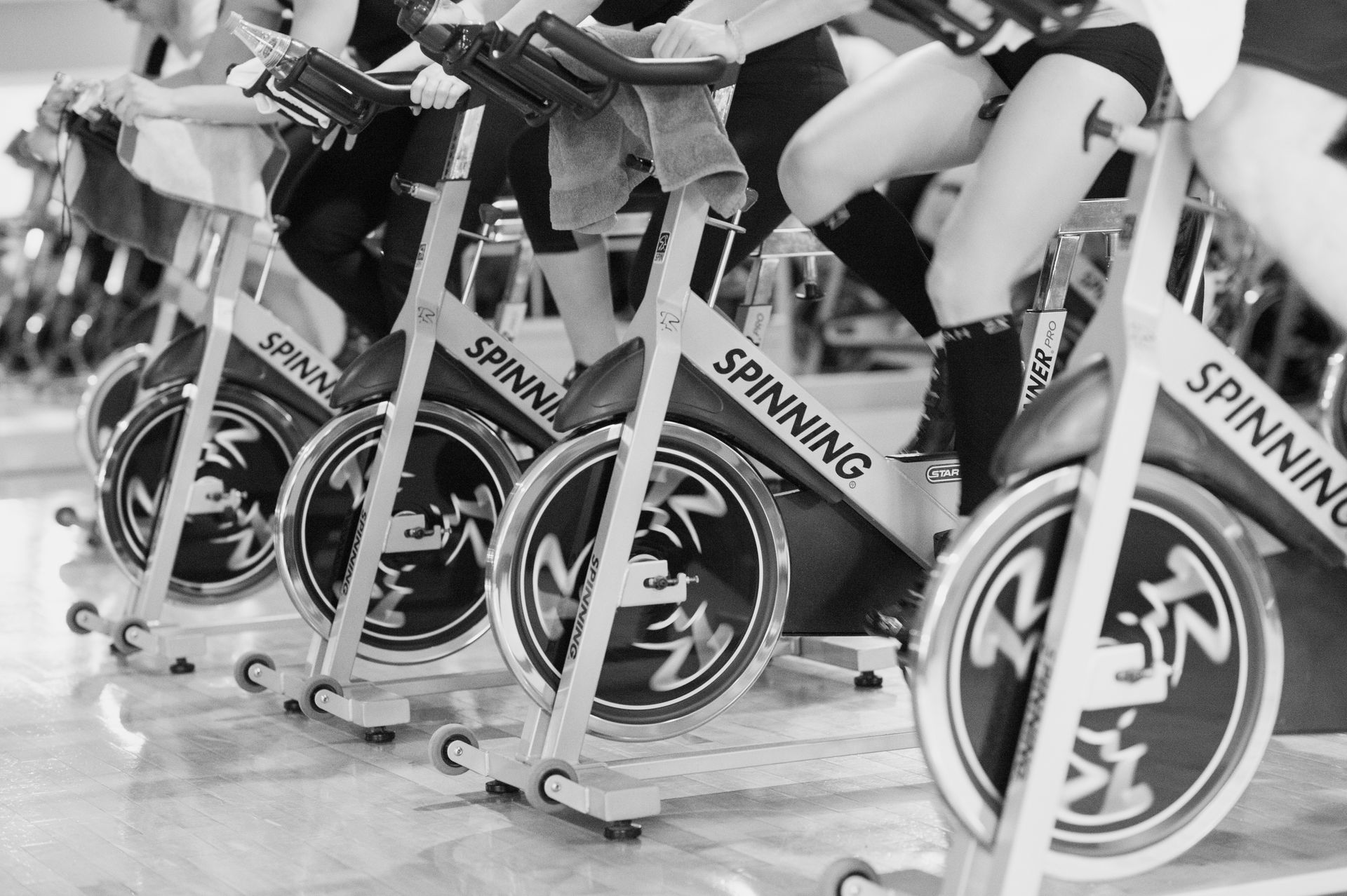 A group of people exercising on indoor stationary spinning bikes in a gym.