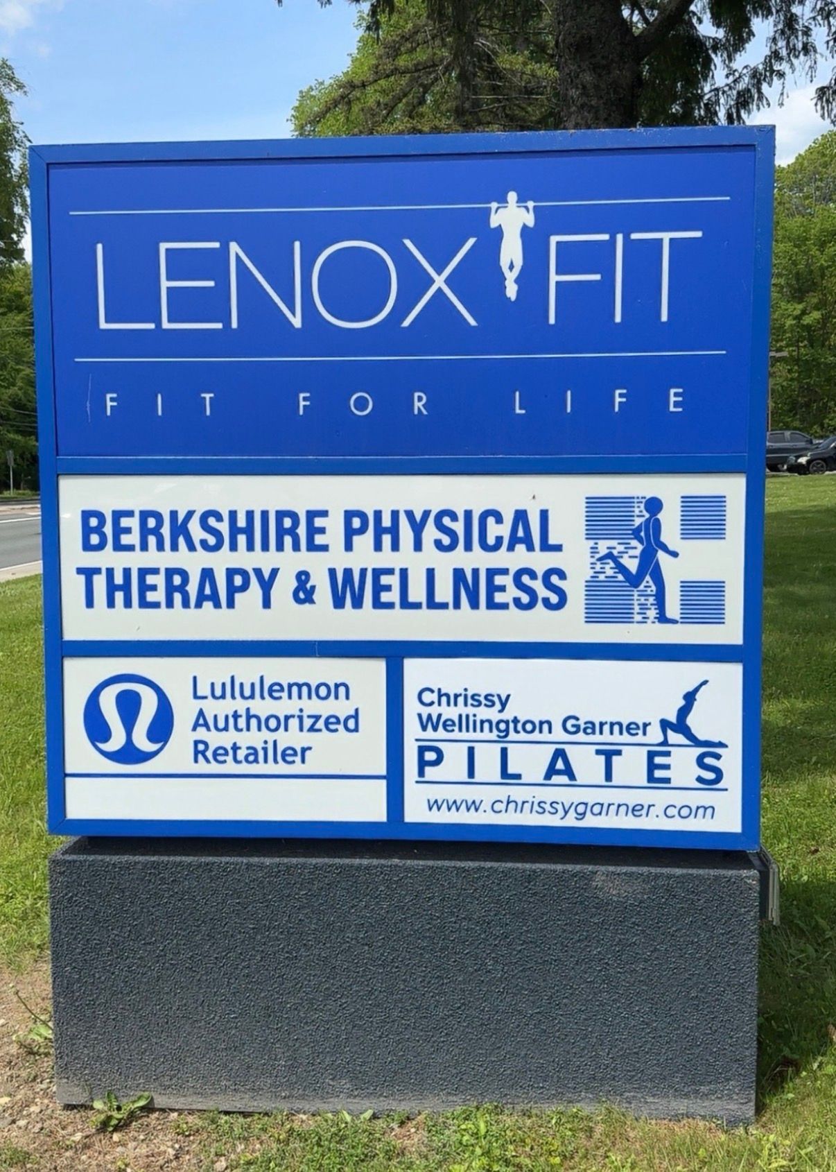 A blue and white outdoor sign for Lenox Fit, featuring Berkshire Physical Therapy, Lululemon, and Chrissy Garner Pilates.