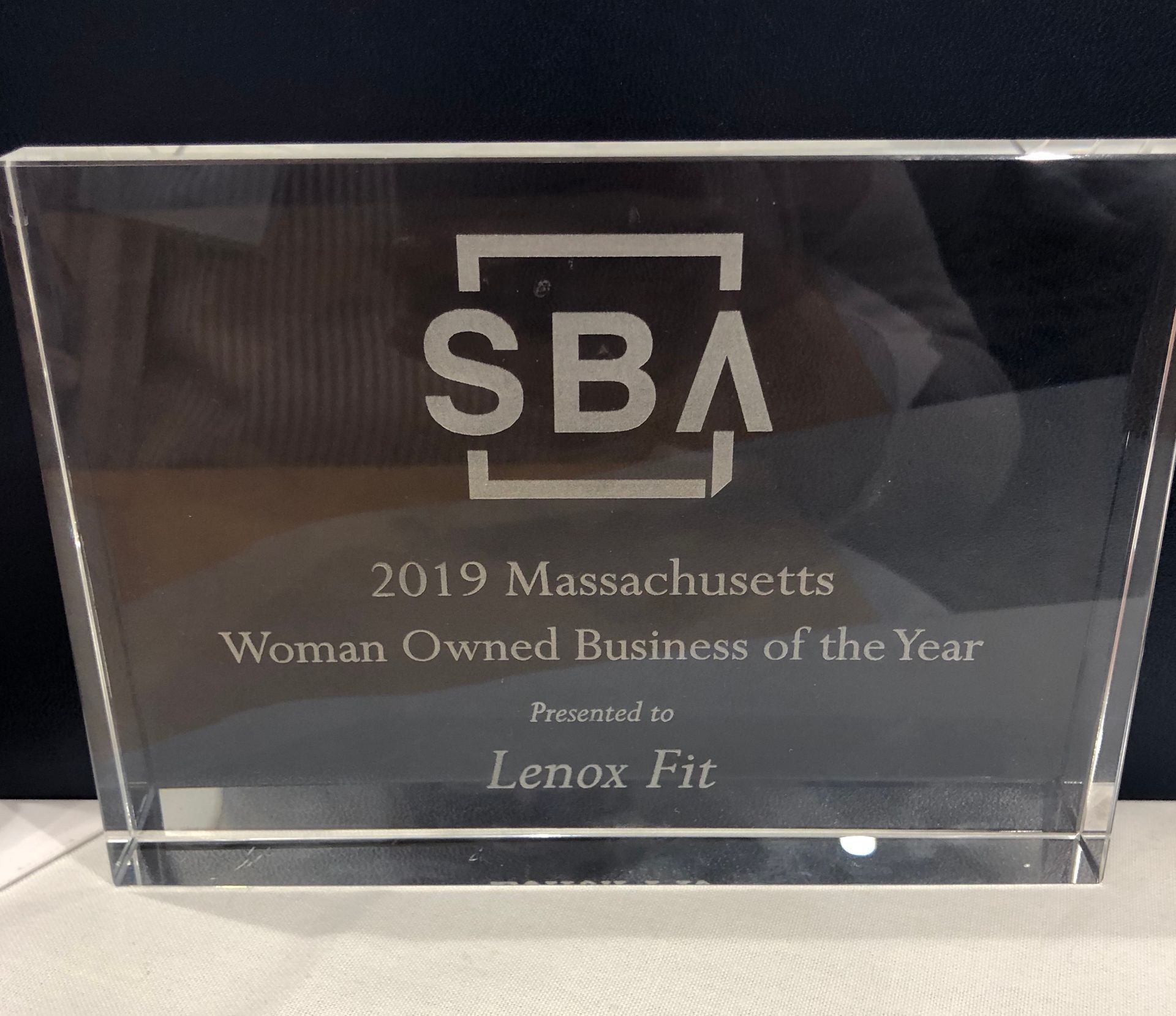 A glass award plaque from the SBA for 2019 Massachusetts Woman Owned Business of the Year, presented to Lenox Fit.