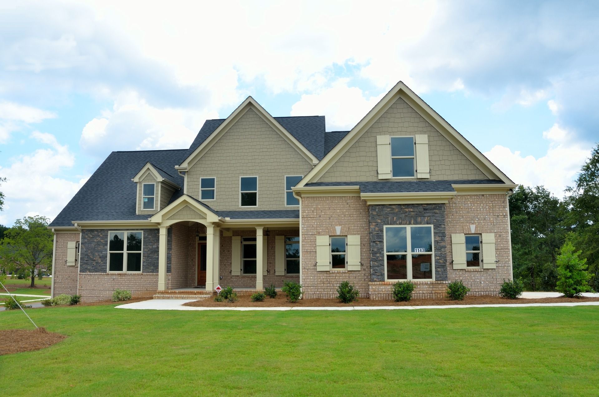 A large newly constructed two-story home with a large front yard and beautiful landscaping.
