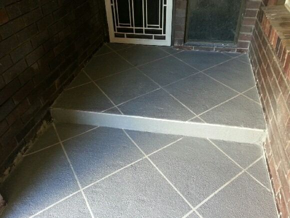 A Tiled Floor Next To A Brick Wall And A Door — Custom Concrete Finishes In Thurgoona, NSW