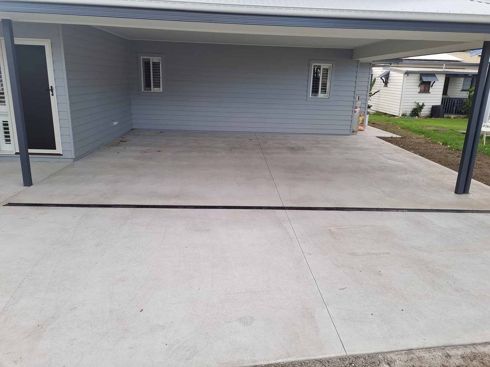 A Concrete Driveway In Front Of A House With A Canopy Over It — Custom Concrete Finishes In Thurgoona, NSW