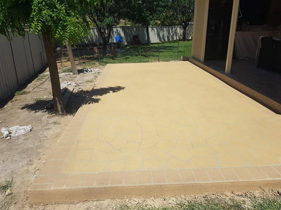 A Concrete Patio With A Tree In The Background And A Fence In The Background — Custom Concrete Finishes In Wodonga, NSW