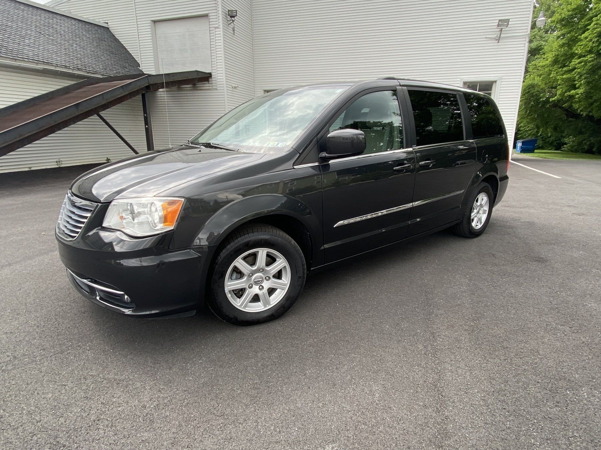 A black minivan is parked in front of a white building.