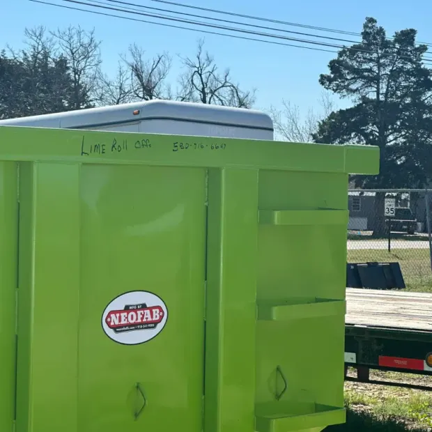 A neon green dumpster by NeoFab featuring handwritten text on its top edge, set against a sunny outdoor background.