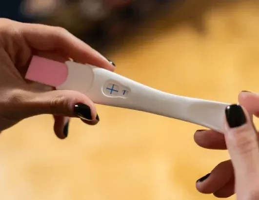 A woman is holding a pregnancy test in her hands.