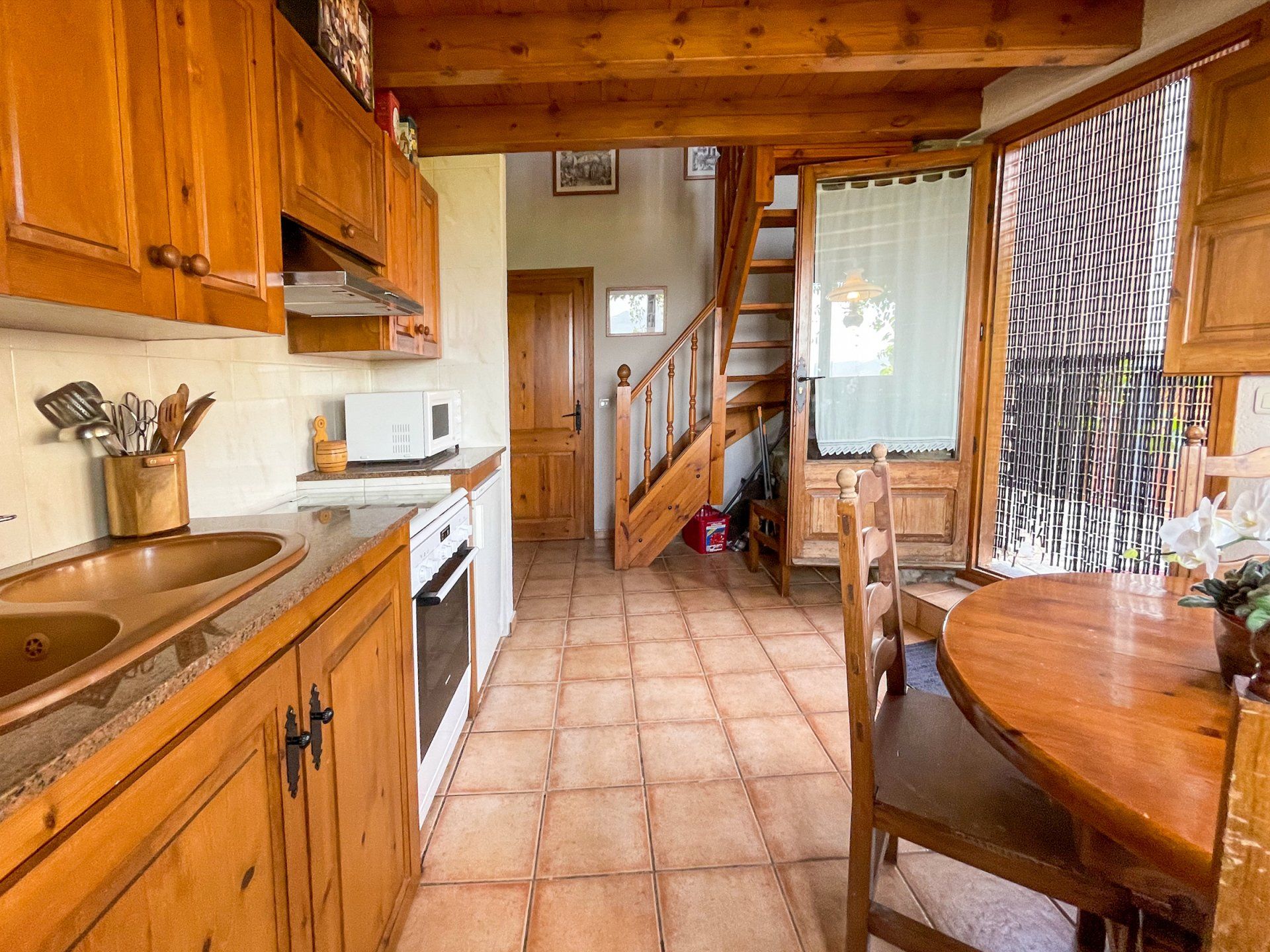 Cuina amb armaris de fusta, terra de rajola i una escala que porta al pis de dalt. Cal Serni