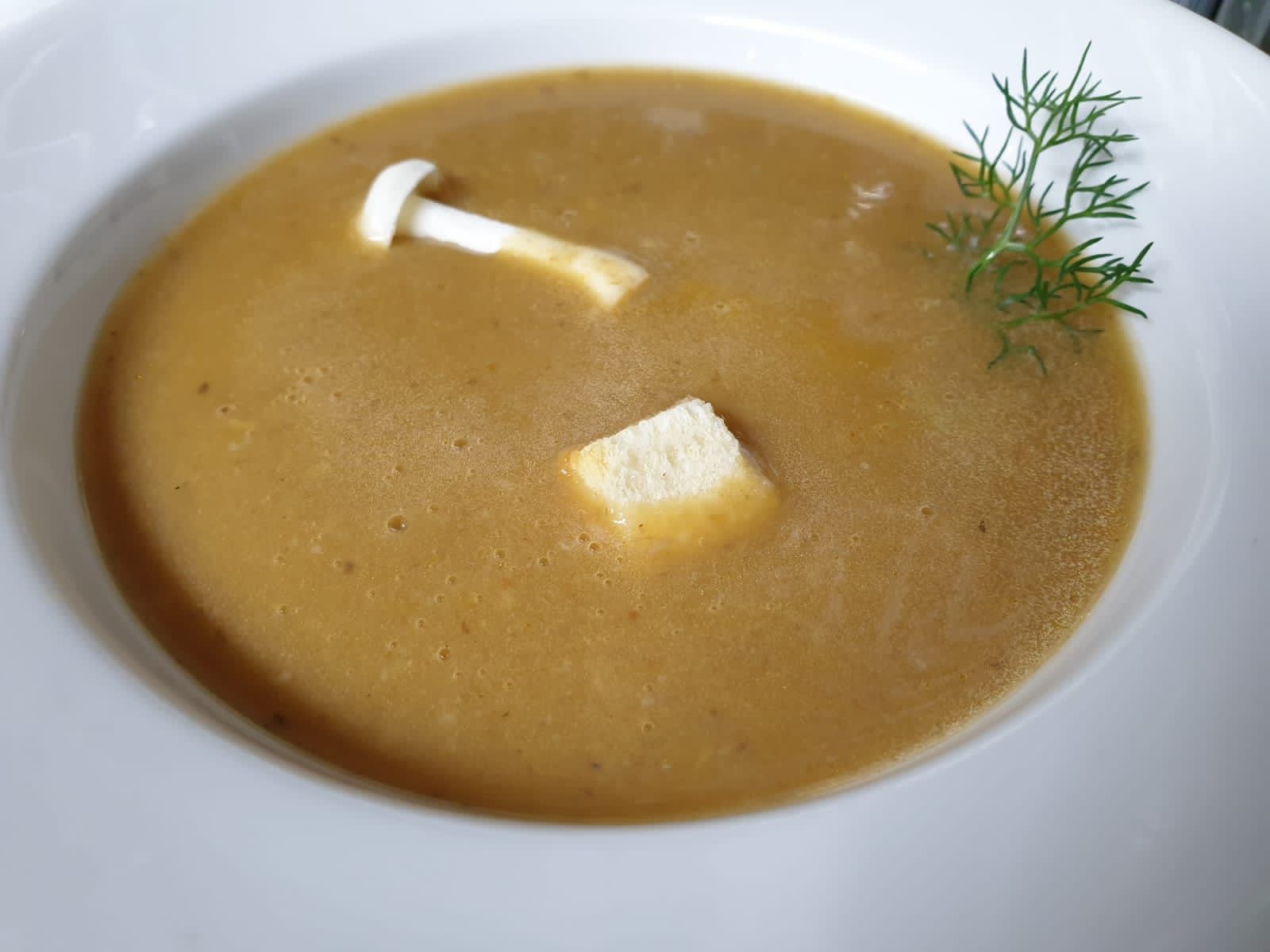 Sopa de bolets en un bol blanc, guarnida amb bolets, crostons i anet. Cal Serni