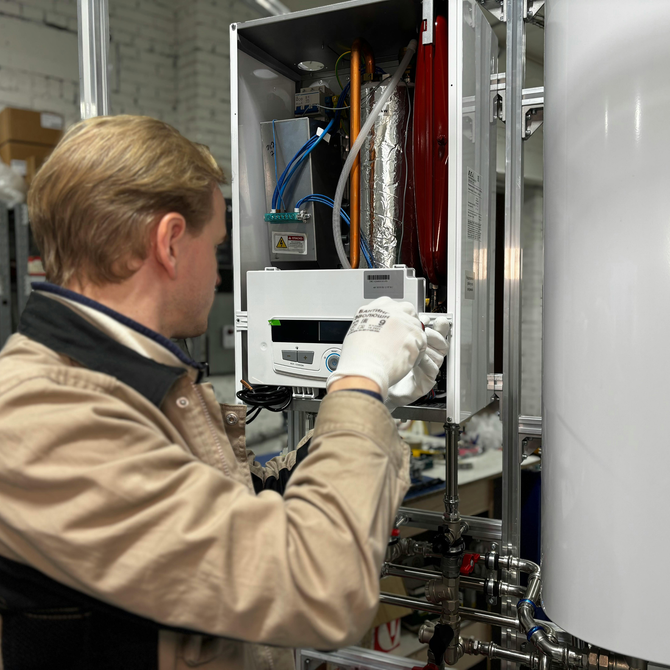 Man wearing gloves working on a white heating unit, industrial setting.