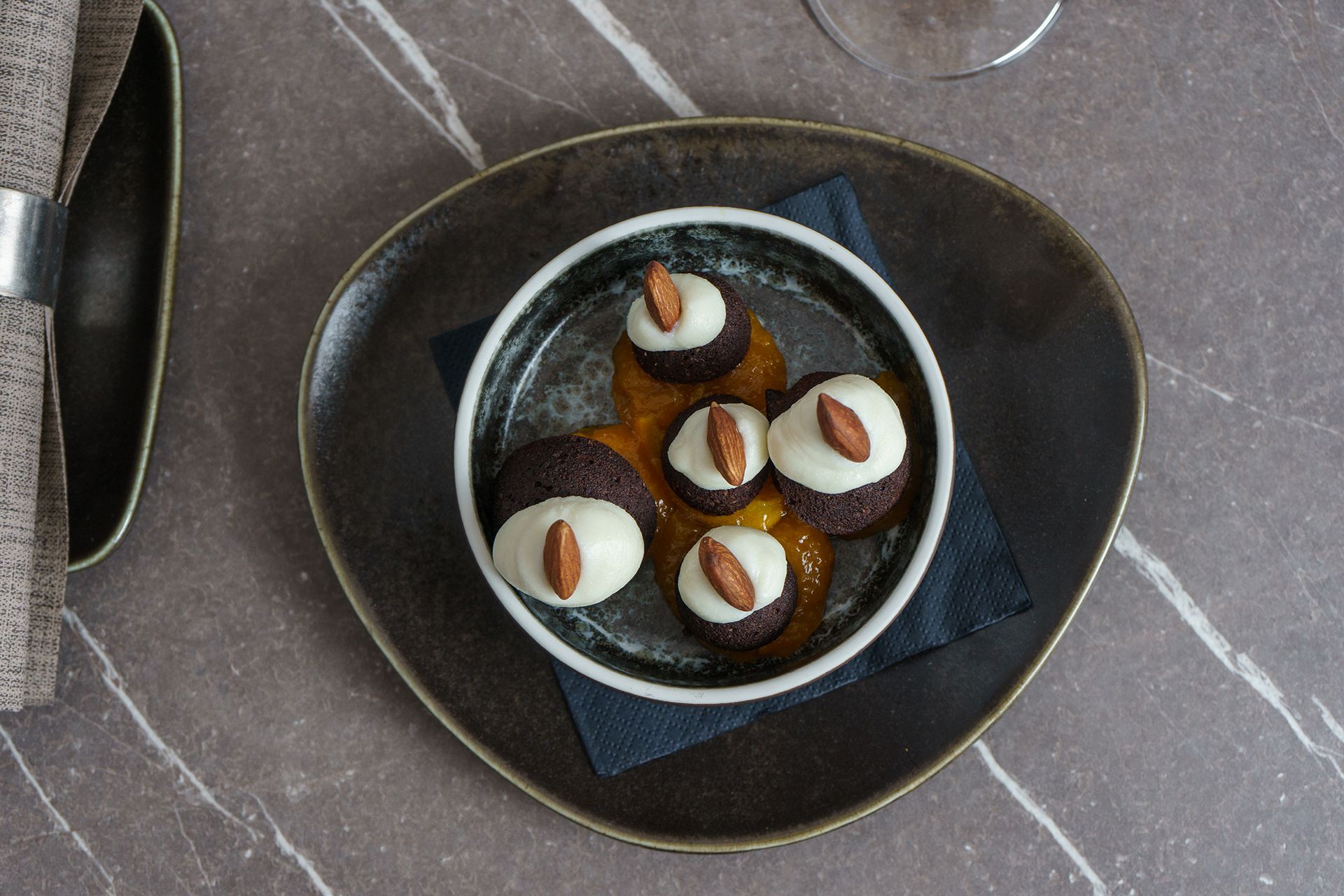 Dessert in una ciotola nera con tartufi al cioccolato ricoperti di bianco su un tavolo scuro