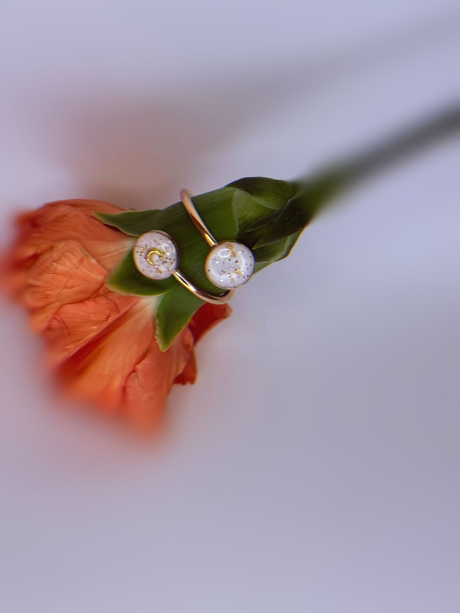 Two rose gold rings with white opal-like stones on a soft beige surface