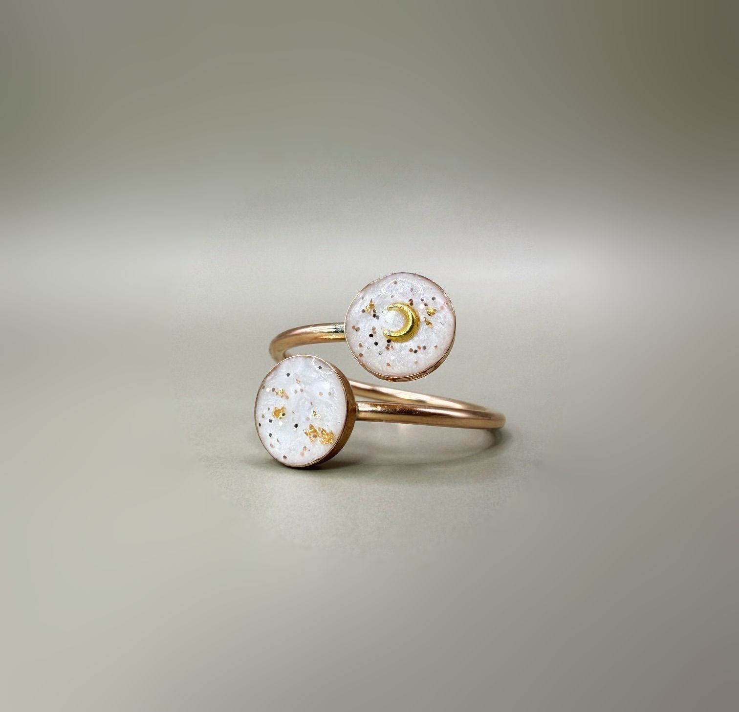 Two rose gold rings with white opal-like stones on a soft beige surface