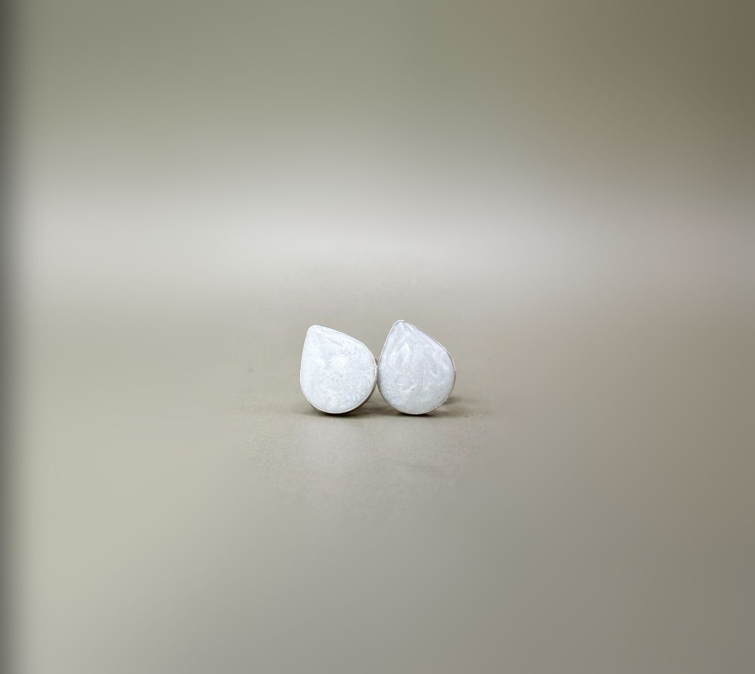 Two white egg-shaped objects on a beige surface against a blurred background