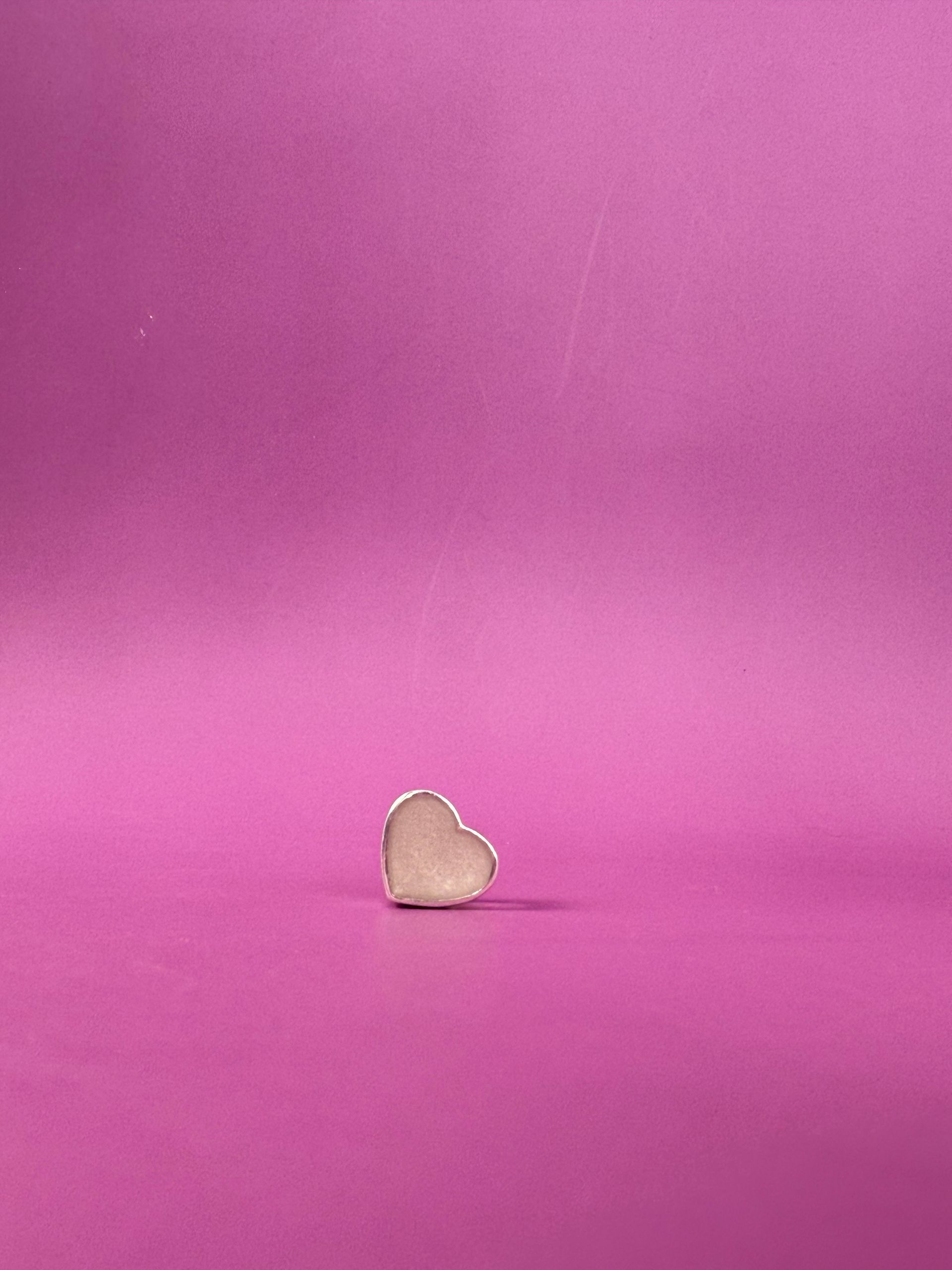 Small beige heart-shaped object on a pink background.