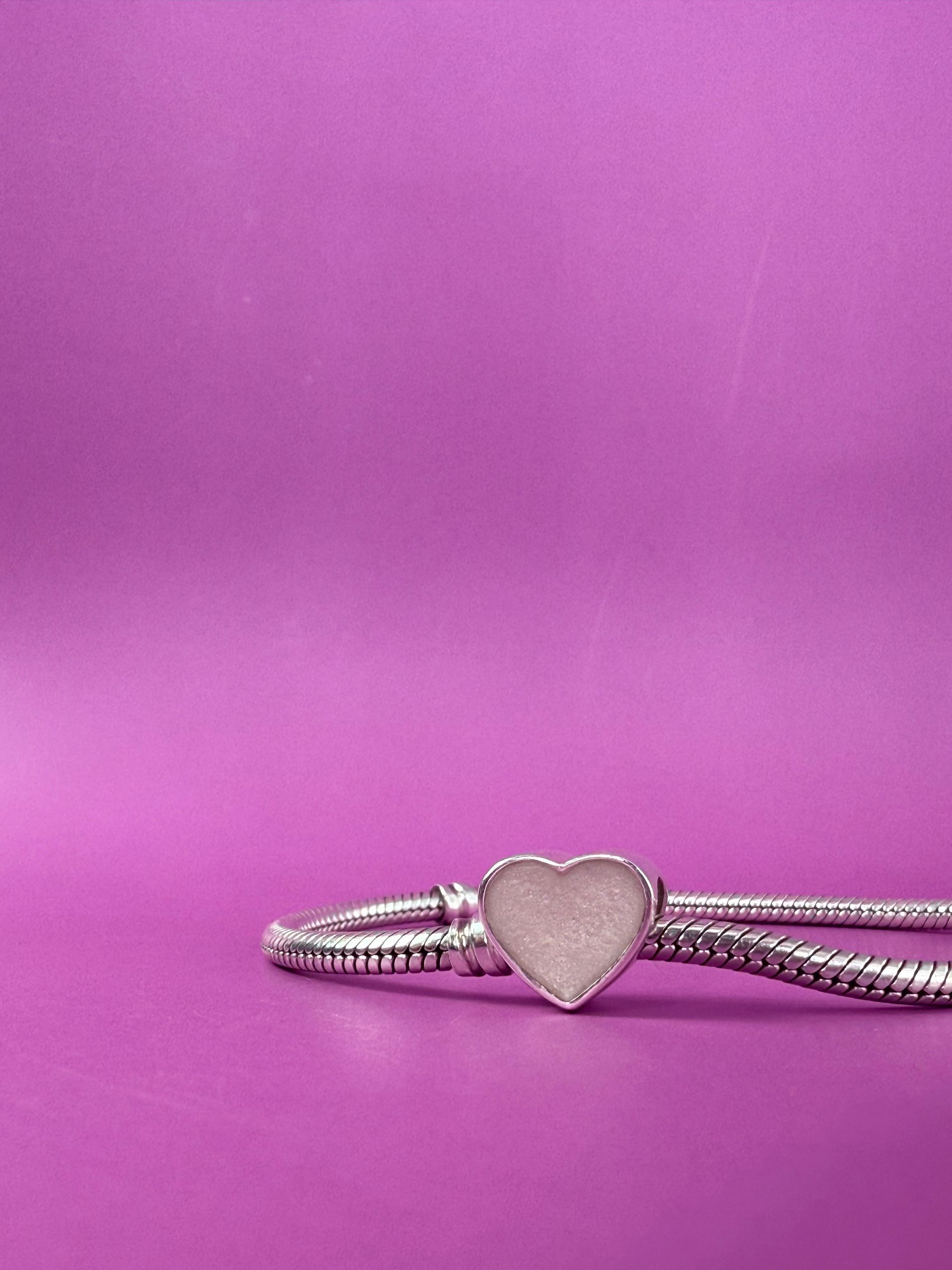 Small beige heart-shaped object on a pink background.