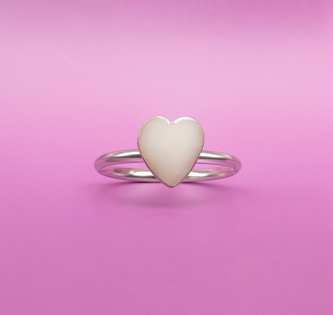 Heart-shaped ring with a white heart on a pink background