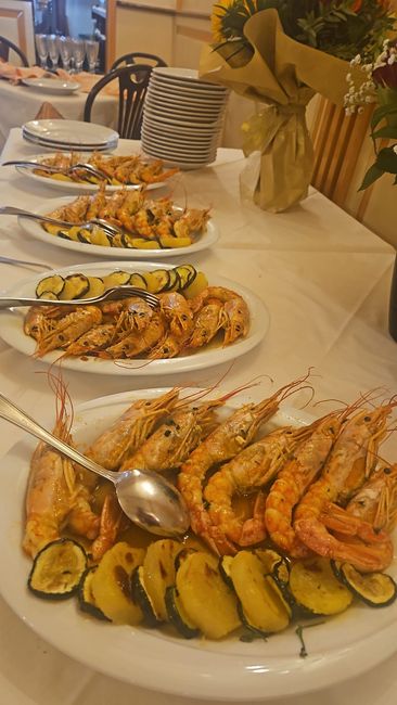 Piatti di gamberi cotti e zucchine grigliate su un tavolo bianco.