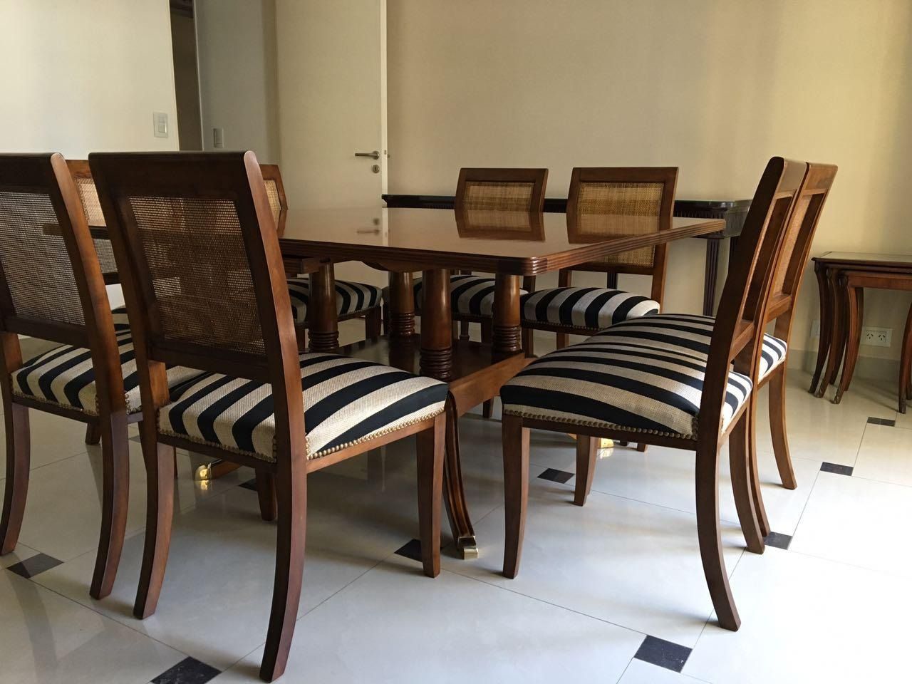Una mesa de comedor de madera con sillas a rayas en una habitación.