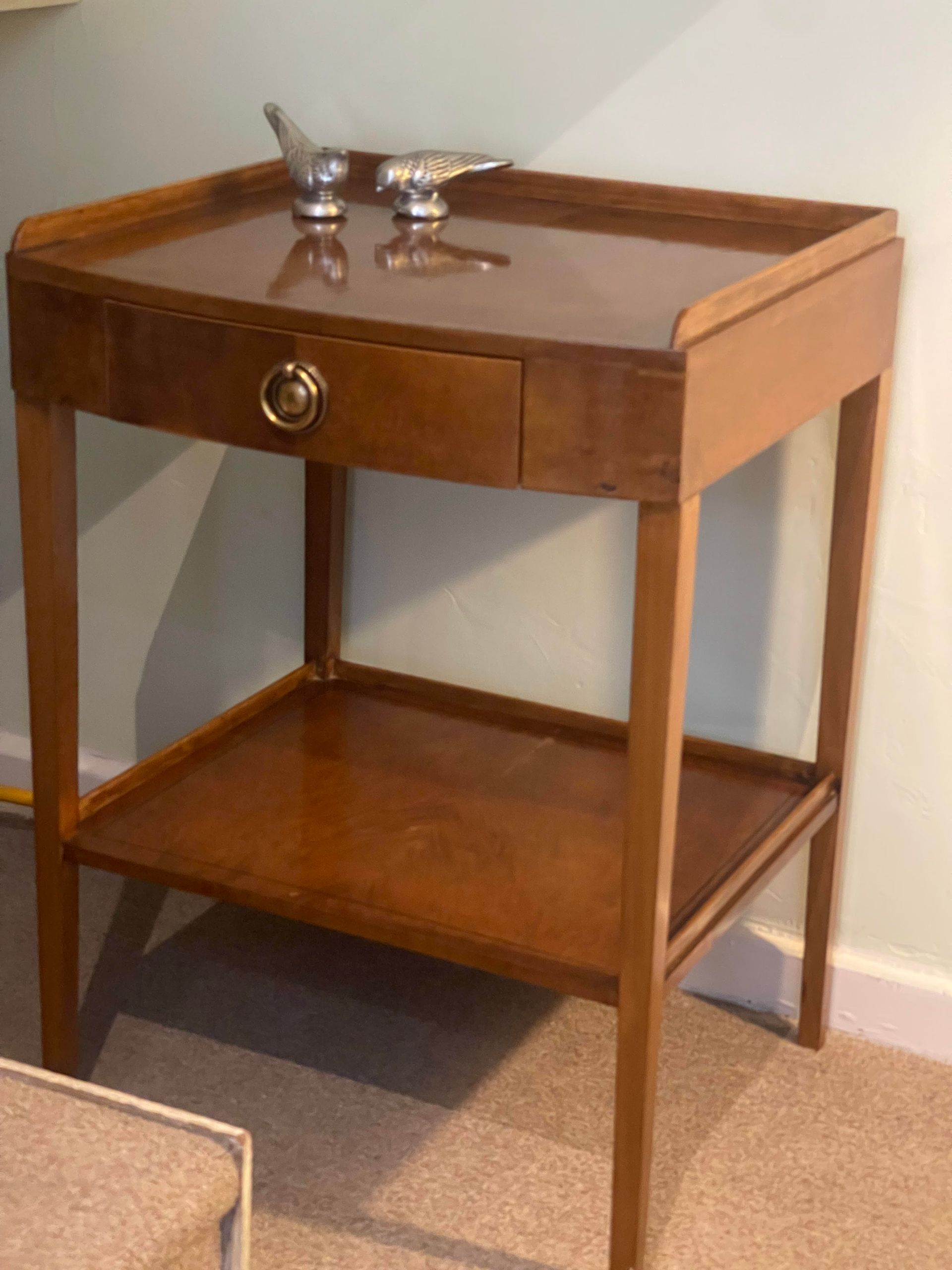 Una pequeña mesa de madera con un cajón y un estante.