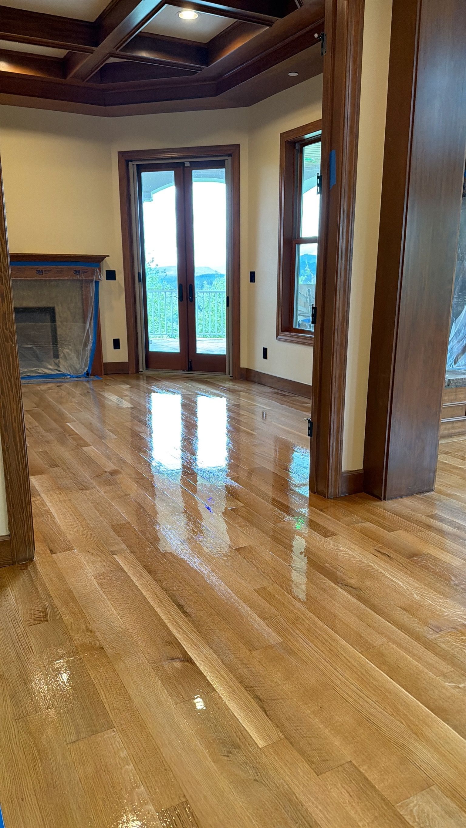 Empty polished wood-floored room with tall windows, exposed beams, and a large column.