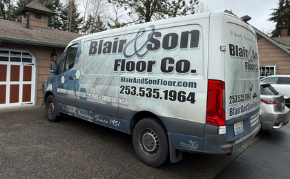 A white Blair & Son Floor Co. service van parked in a driveway in front of a brick house.
