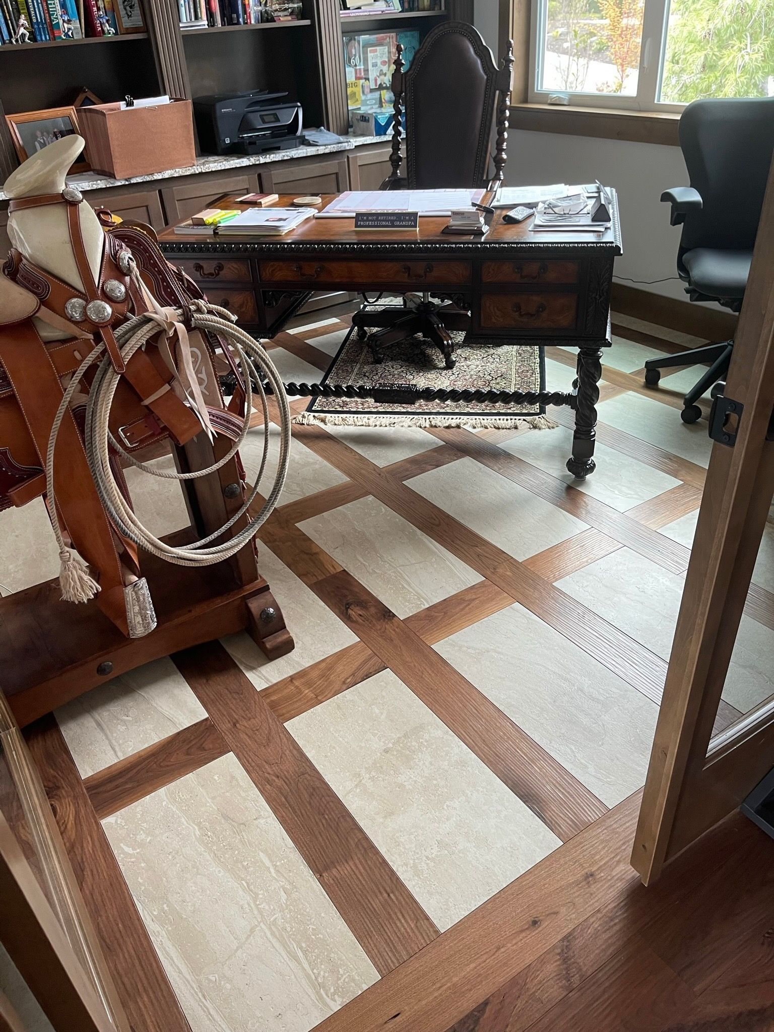 Cluttered home office with a desk, chair, and rug featuring a large decorative model ship in the foreground