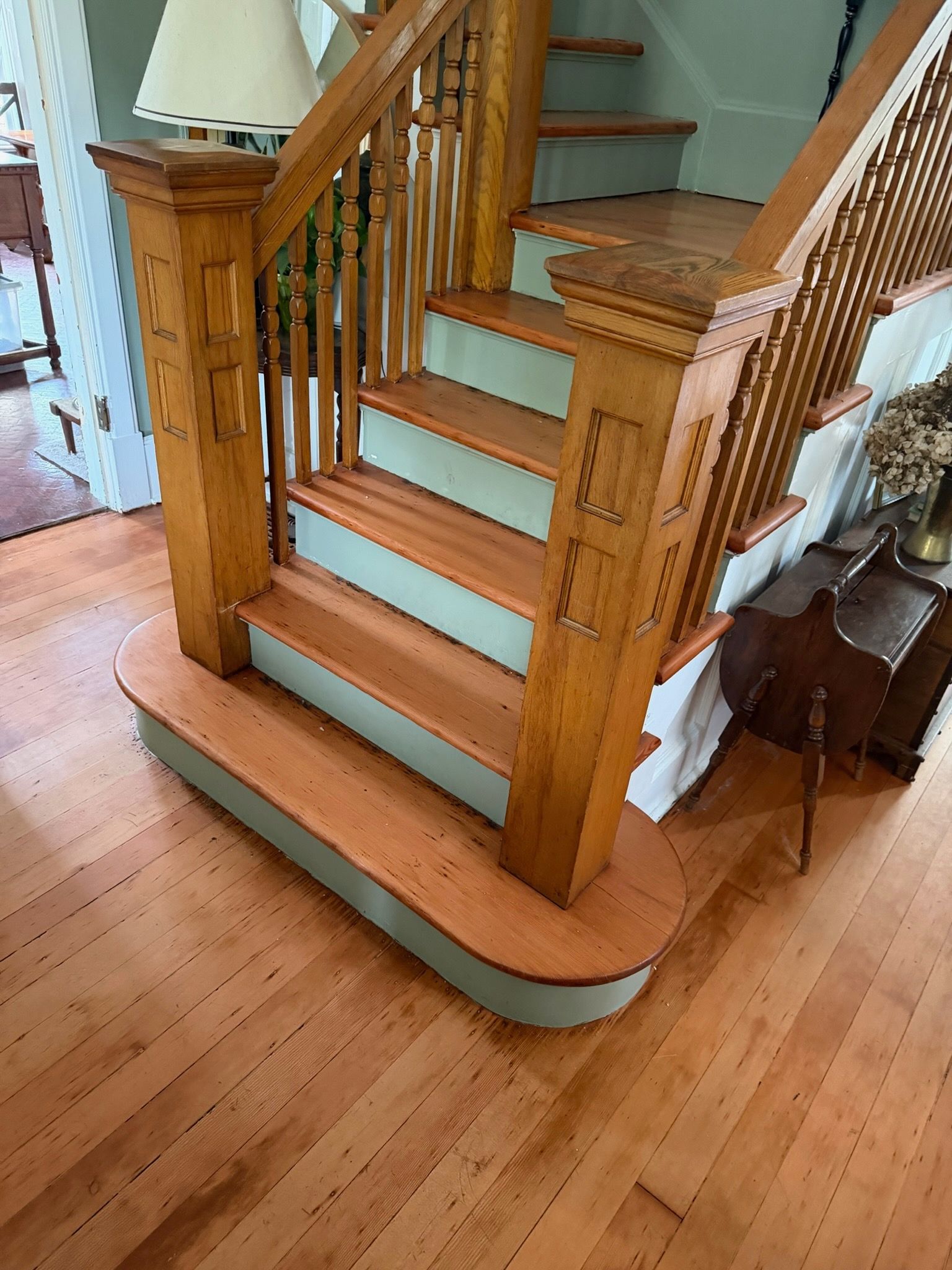 Wooden staircase with light blue carpeted steps and curved bottom trim in a home interior