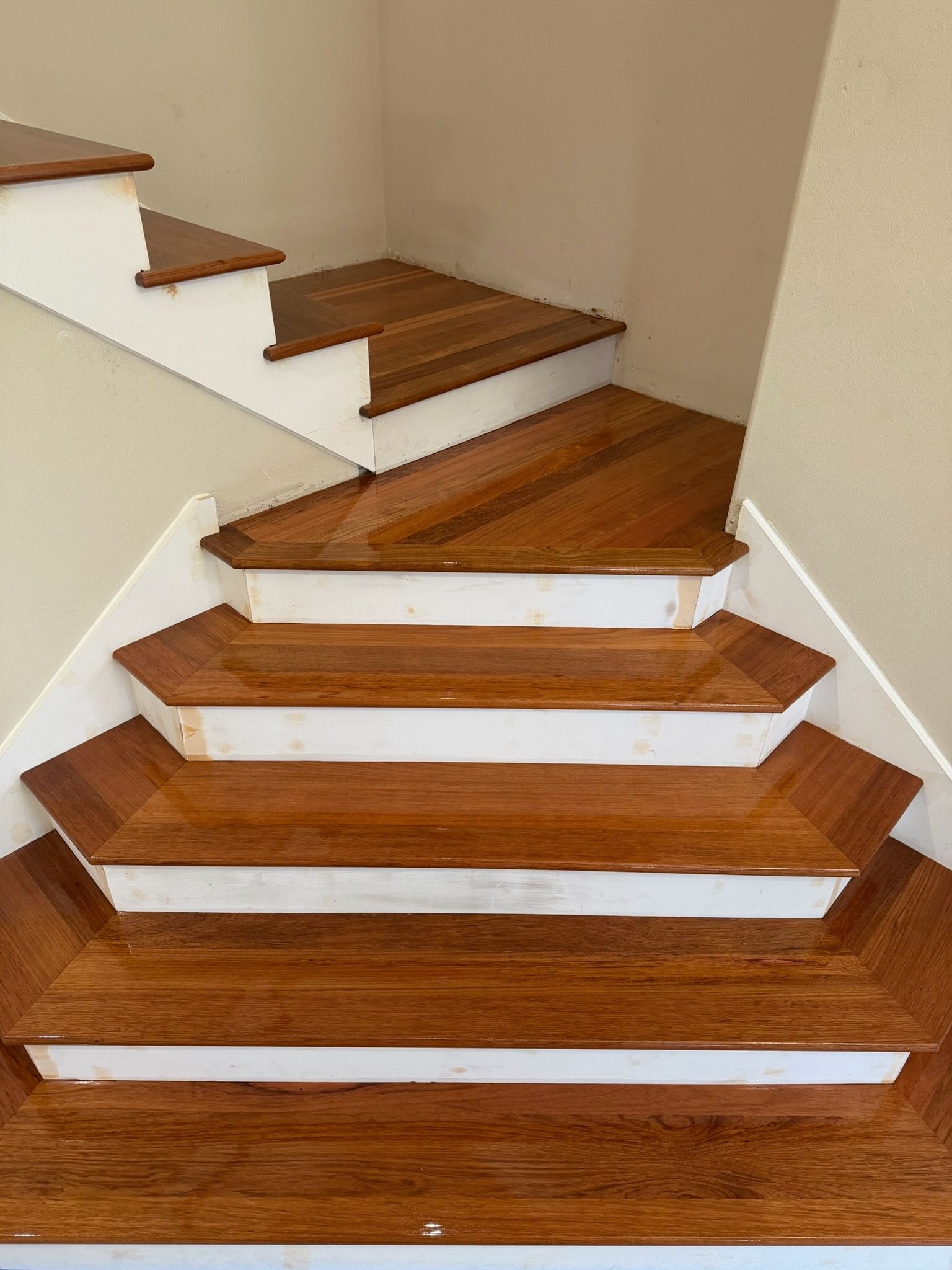 Indoor staircase with wood steps and white walls, showing a sharp turn and uneven step layout.